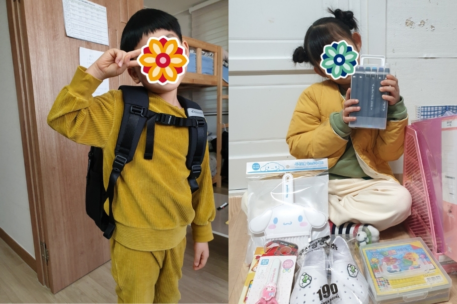 Two children show new school supplies and backpacks inside a children’s home. Their faces are covered with stickers.