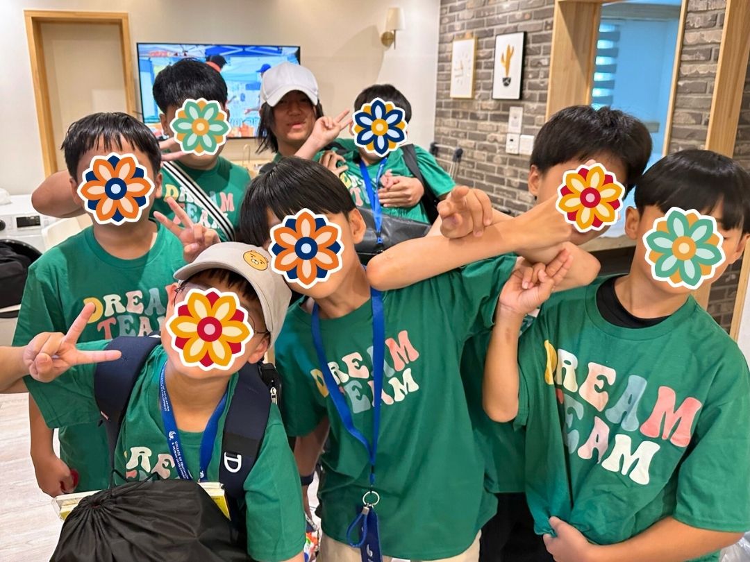 Children wearing green Dream Team shirts posing together during a KKOOM summer camp event.