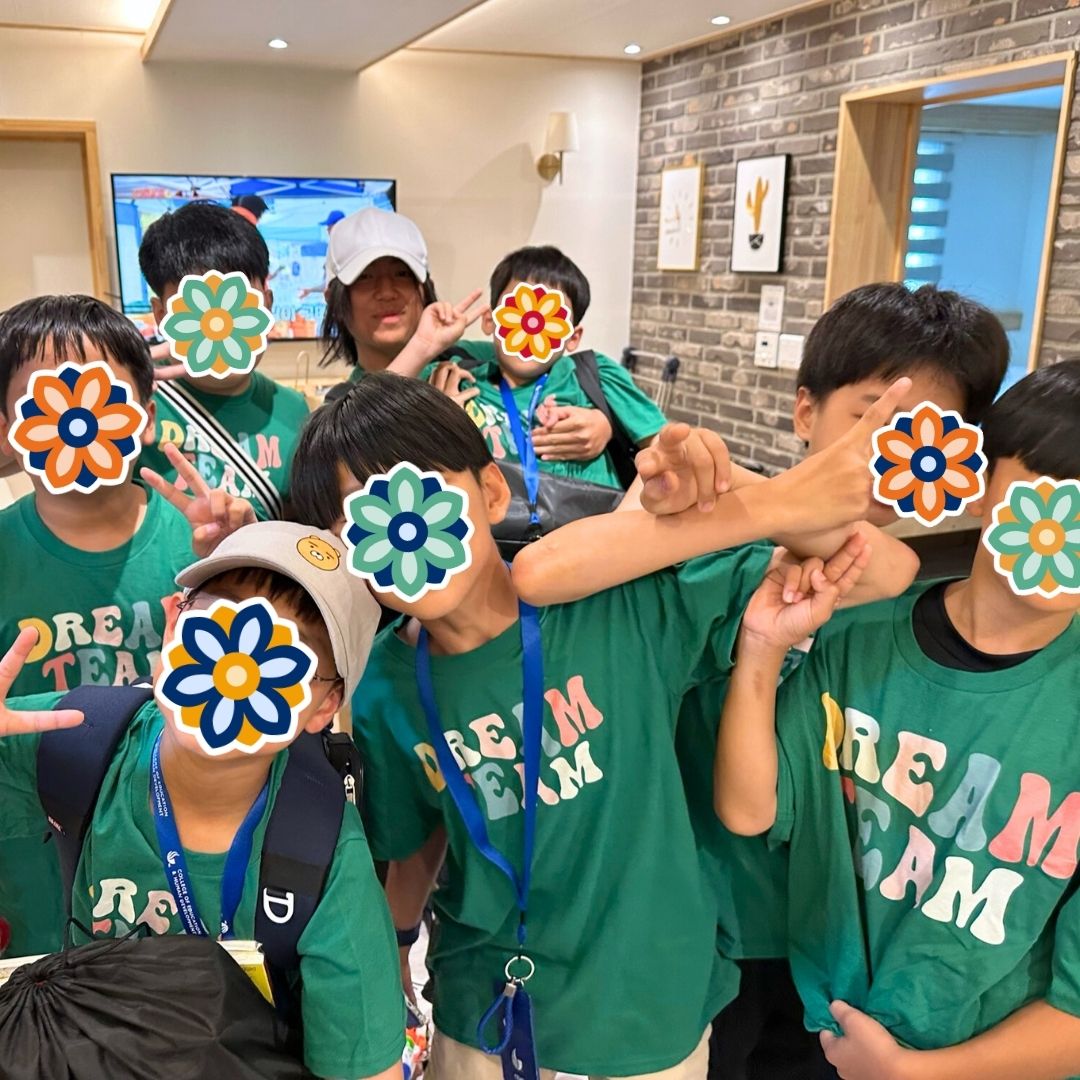 Children wearing green Dream Team shirts posing together during a KKOOM summer camp event.