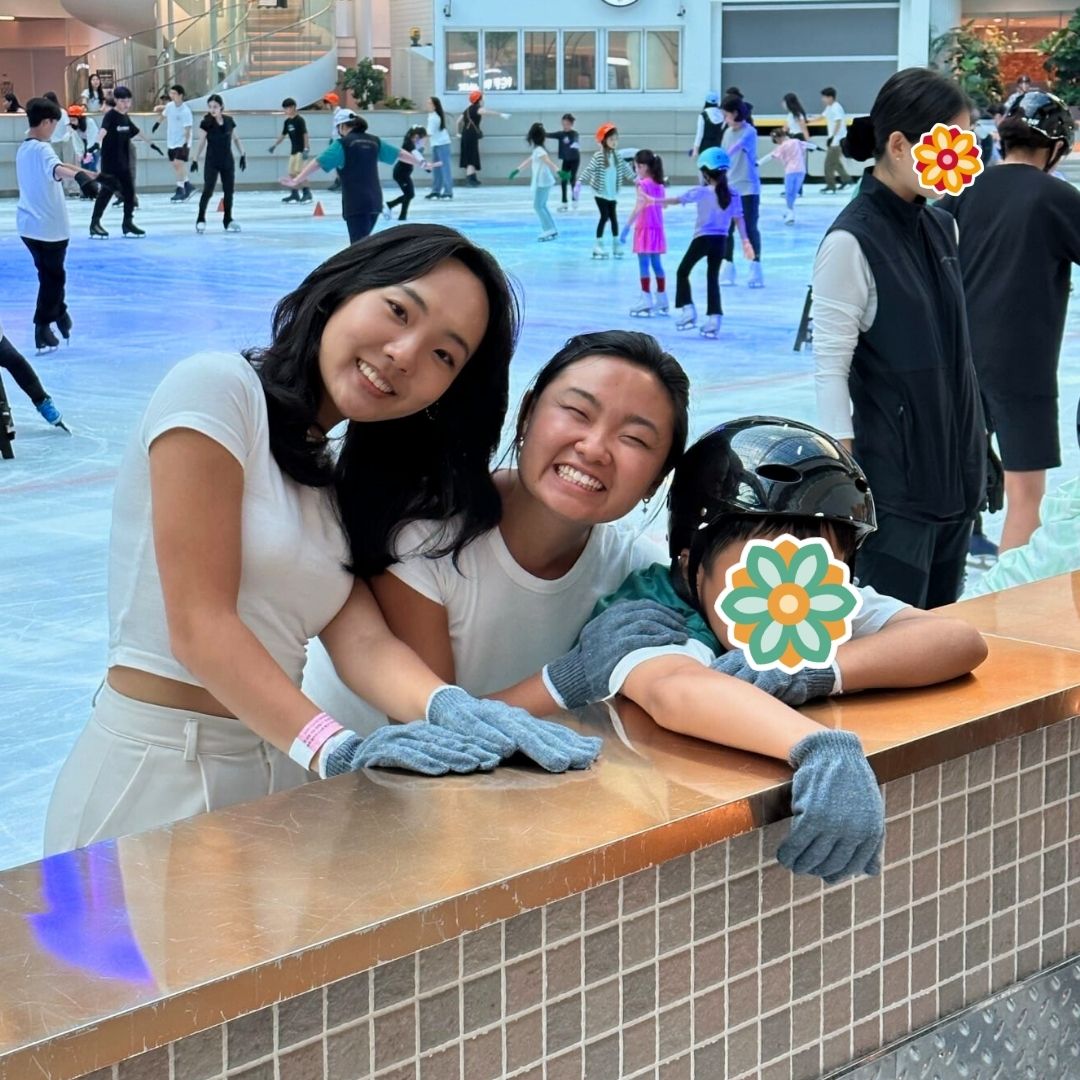 Volunteers and a child ice skating together during a KKOOM winter activity.