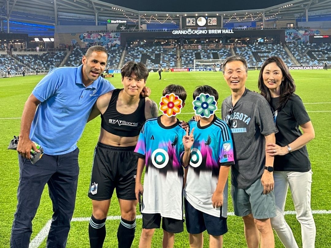 Children and volunteers posing on a soccer field stadium floor during a sports game.