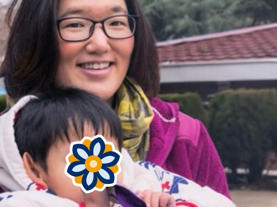 KKOOM volunteer holding a young child and spending time together outdoors.