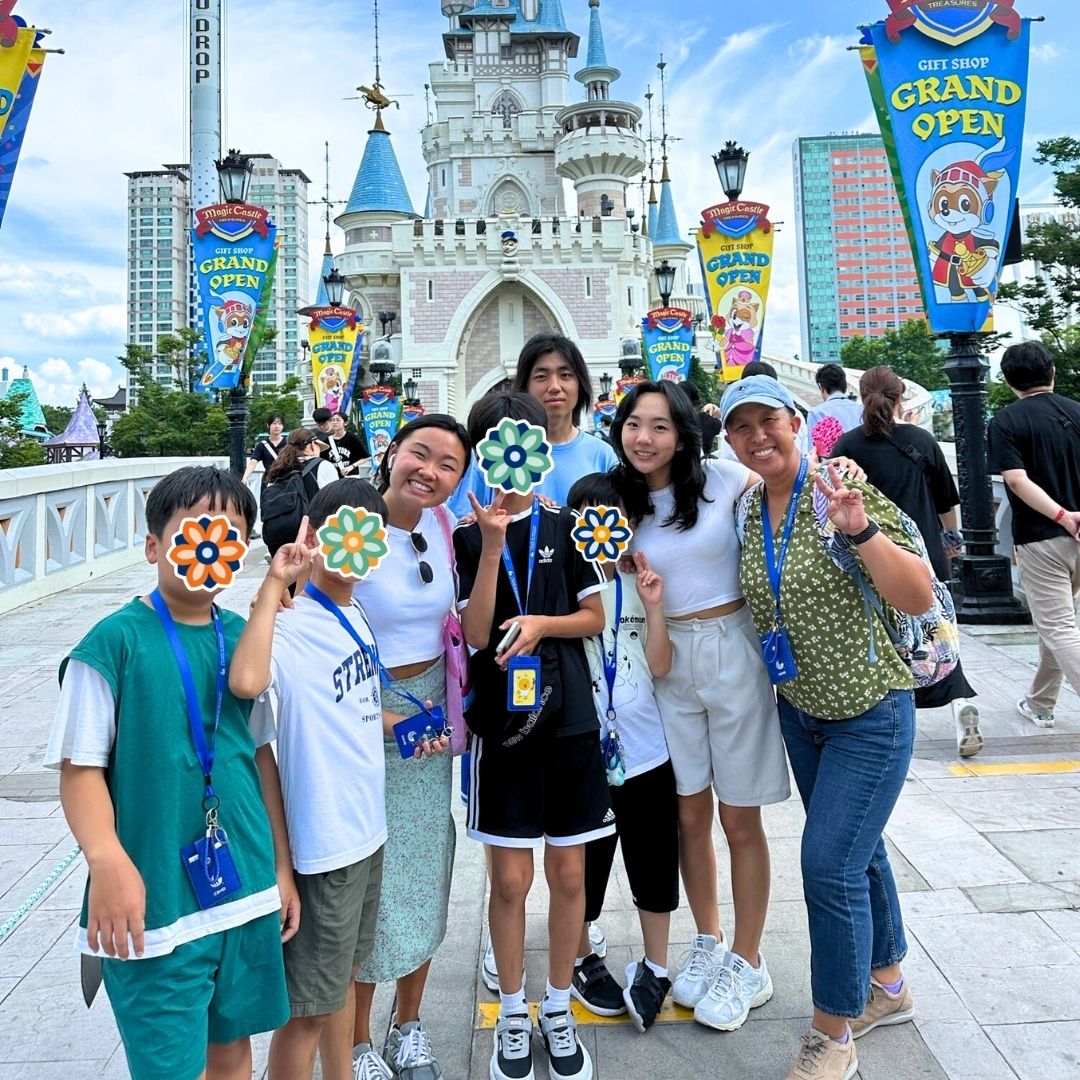 Children and KKOOM staff and intern posing together at an amusement park during KKOOM's summer camp.