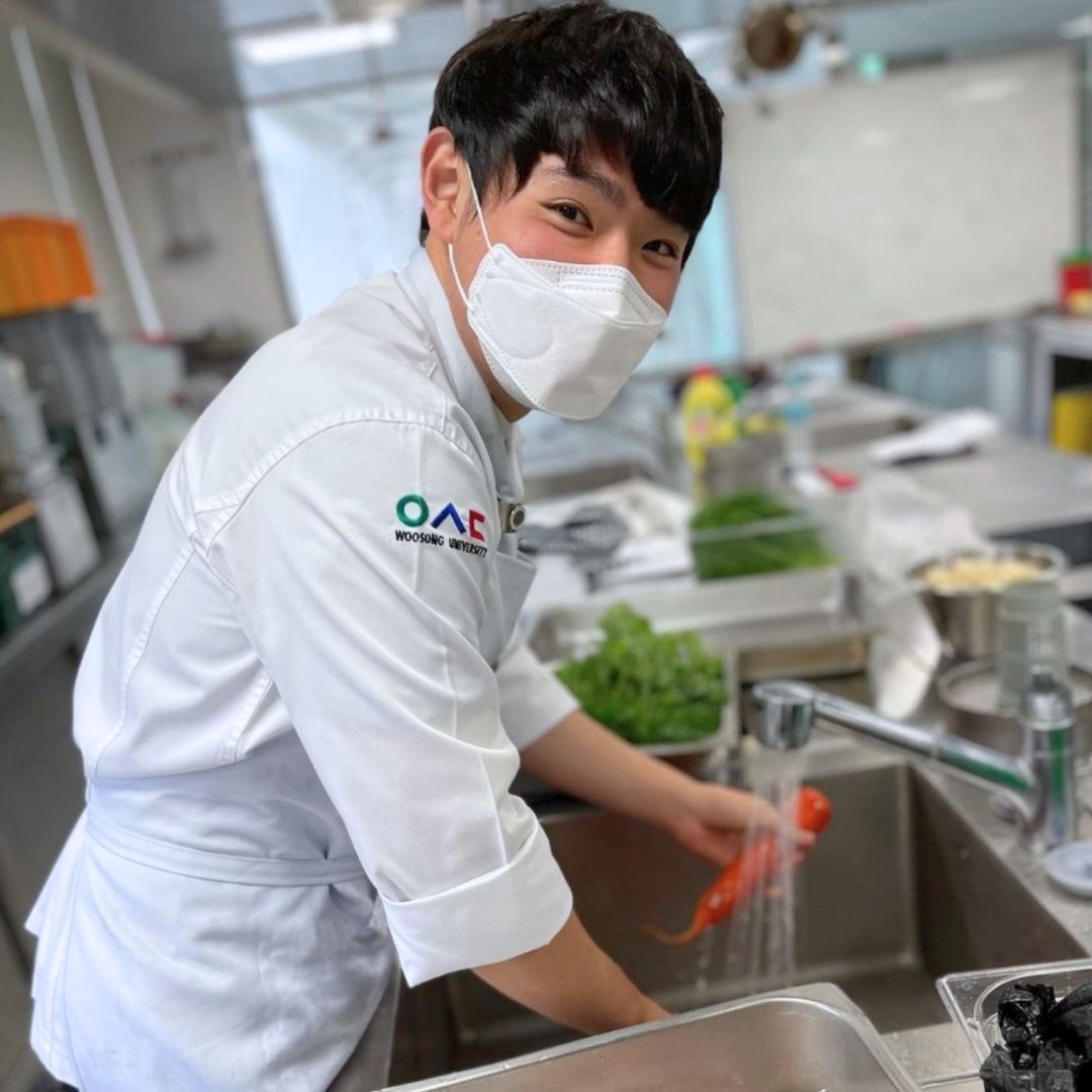 Student in a kitchen classroom learning culinary skills as part of a KKOOM scholarship program.