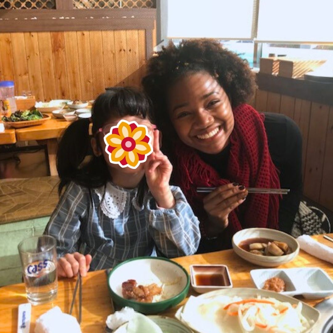 Volunteer sharing a meal and smiling with a child during a KKOOM outing.