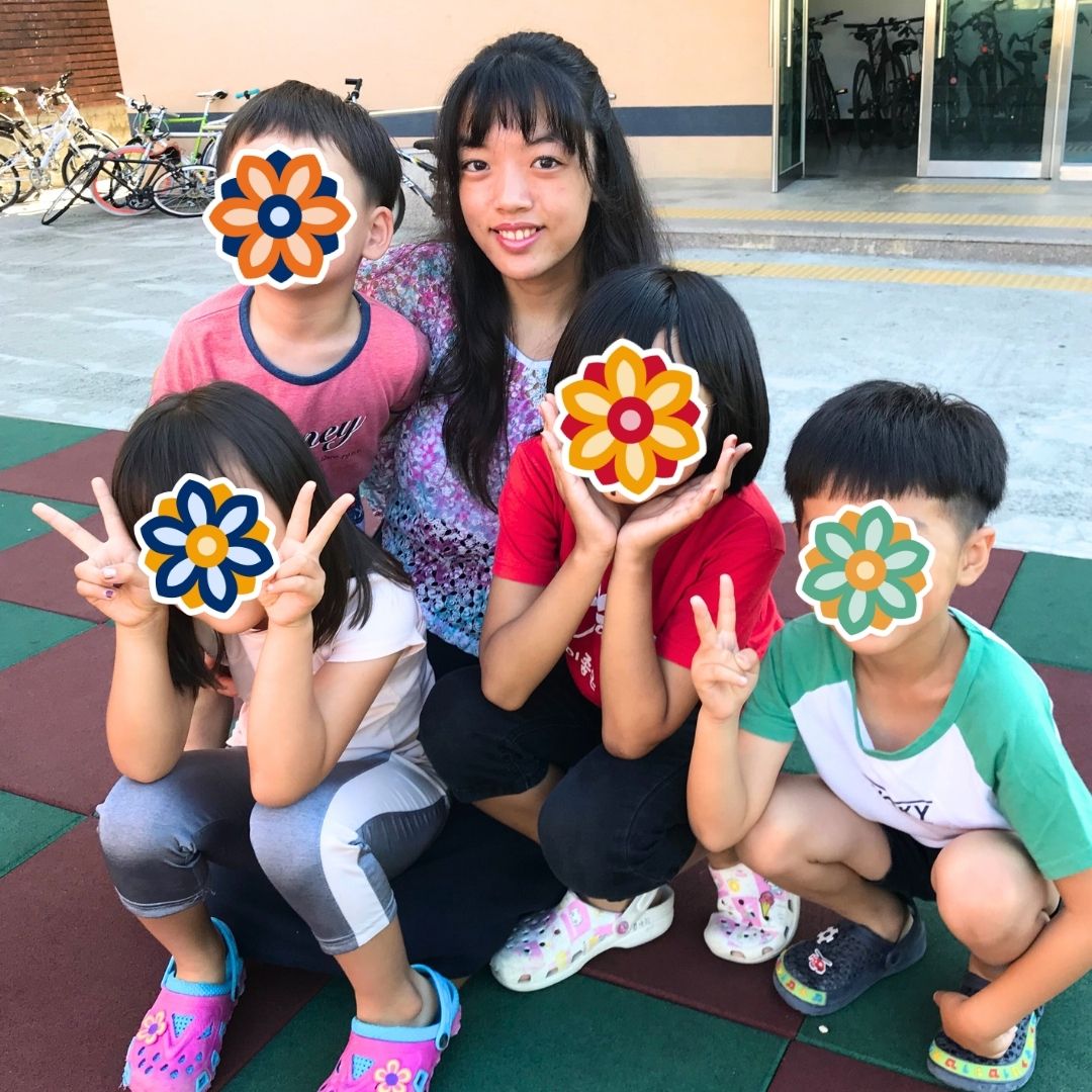 Volunteer spending time with a group of children outdoors during a KKOOM activity.