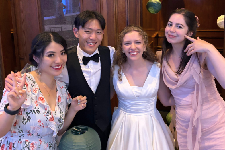 Four adults standing together at a celebration, smiling, with faces partially obscured for privacy.