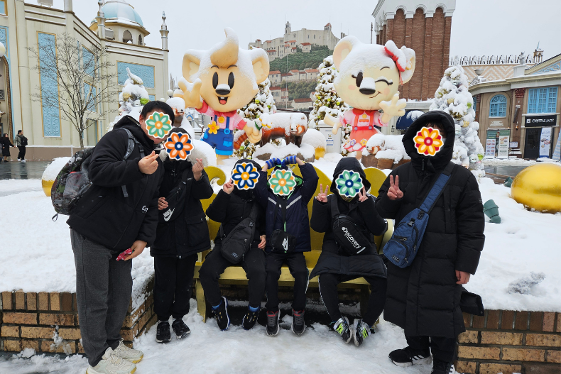 Group of youth and adults posing outdoors at Everland amusement park during winter, smiling and celebrating a holiday outing together.