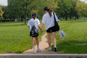Yumin walking together with a student through a green park.