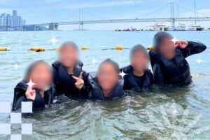 Campers posing playfully in the ocean with a bridge in the background.