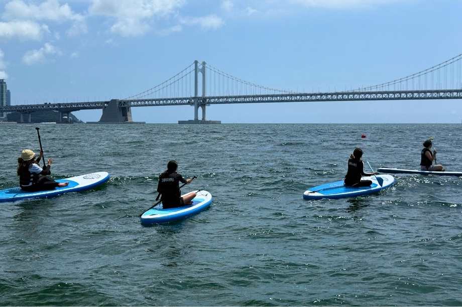 Students paddleboarding on the water near Busan's Gwangalli Beach during camp.