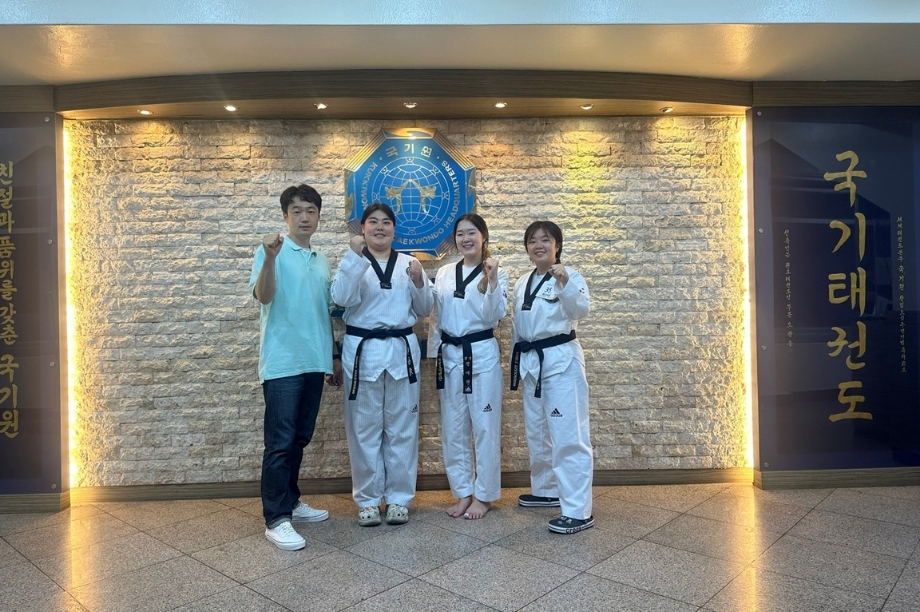 Vivian and fellow taekwondo teammates posing in doboks at the Kukkiwon in Seoul.